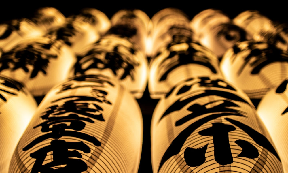 Hileras de faroles de papel chōchin japoneses iluminados con kanji negros en una calle