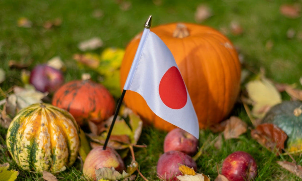 Calabaza de Halloween tallada junto a una bandera japonesa entre calabazas de otoño