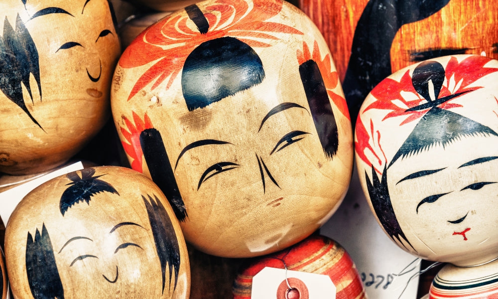 Muñecas kokeshi japonesas tradicionales: primer plano de cabezas de madera pintadas a mano de Tōhoku, con diseños regionales