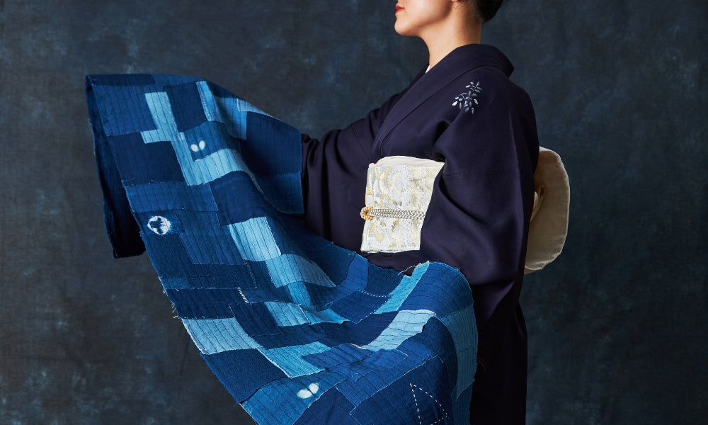 Textil de parches boro japonés en algodón de añil con puntadas corridas sashiko visibles, llevado por un modelo con kimono oscuro