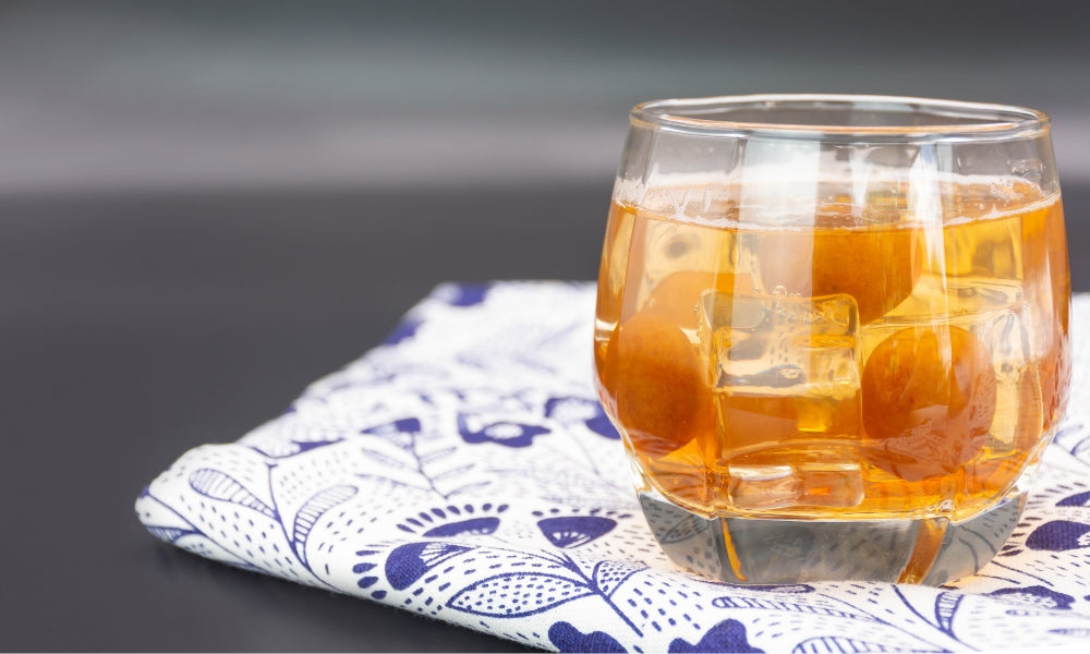 Vaso de umeshu, el vino de ciruela japonés, servido con hielo y con frutas ume enteras en el fondo