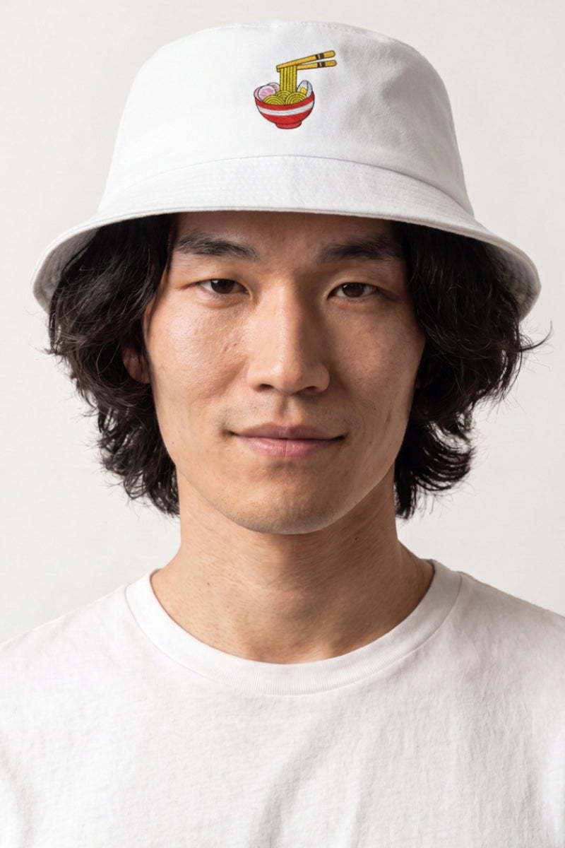 Colección de bucket hats: hombre con bucket hat de algodón blanco bordado con un bol de ramen y palillos, estilo streetwear japonés