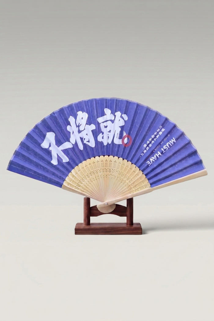 Abanico plegable japonés 'Honiko' abierto sobre su soporte — amplia caligrafía blanca a pincel sobre hoja azul índigo y varillas de bambú claro