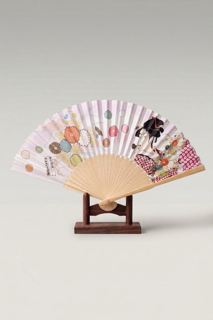 Abanico plegable japonés 'Tsushima' abierto sobre su soporte — geisha en estampa ukiyo-e y crisantemos sobre hoja lila muy pálida