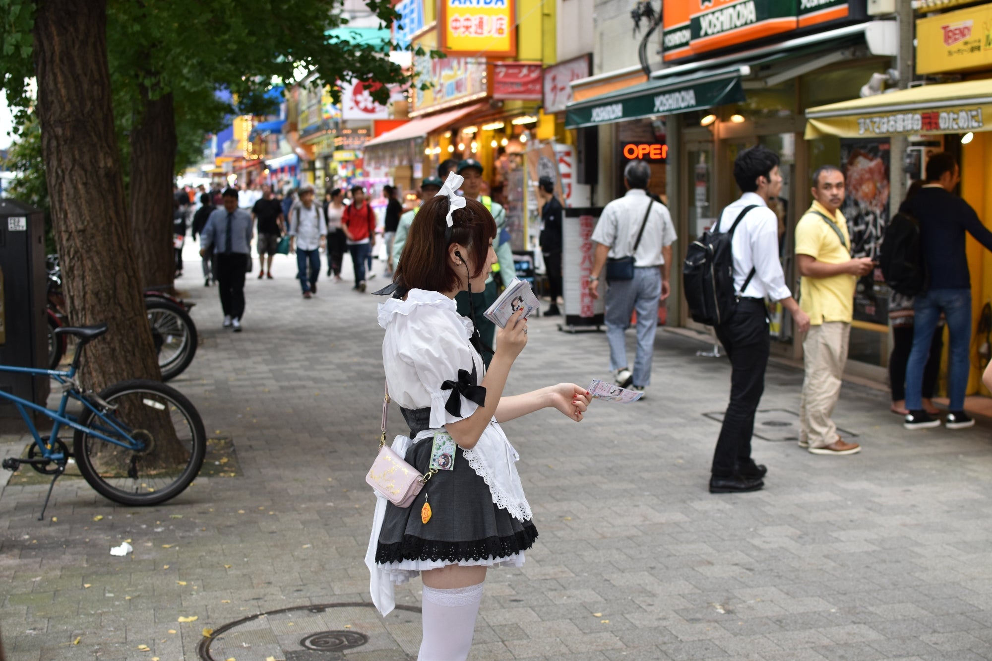 Camarera vestida con uniforme de maid café repartiendo folletos en Akihabara, en el corazón de la cultura otaku y de los cafés temáticos japoneses.