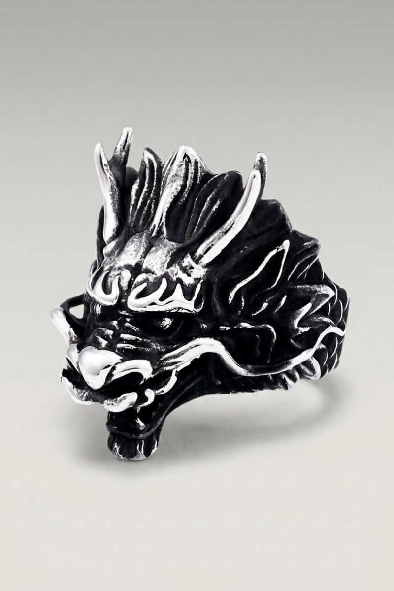 Anillo 'Sephiro' — cabeza de dragón de acero con la boca abierta, escamas y colmillos detallados, foto de producto sobre fondo gris claro