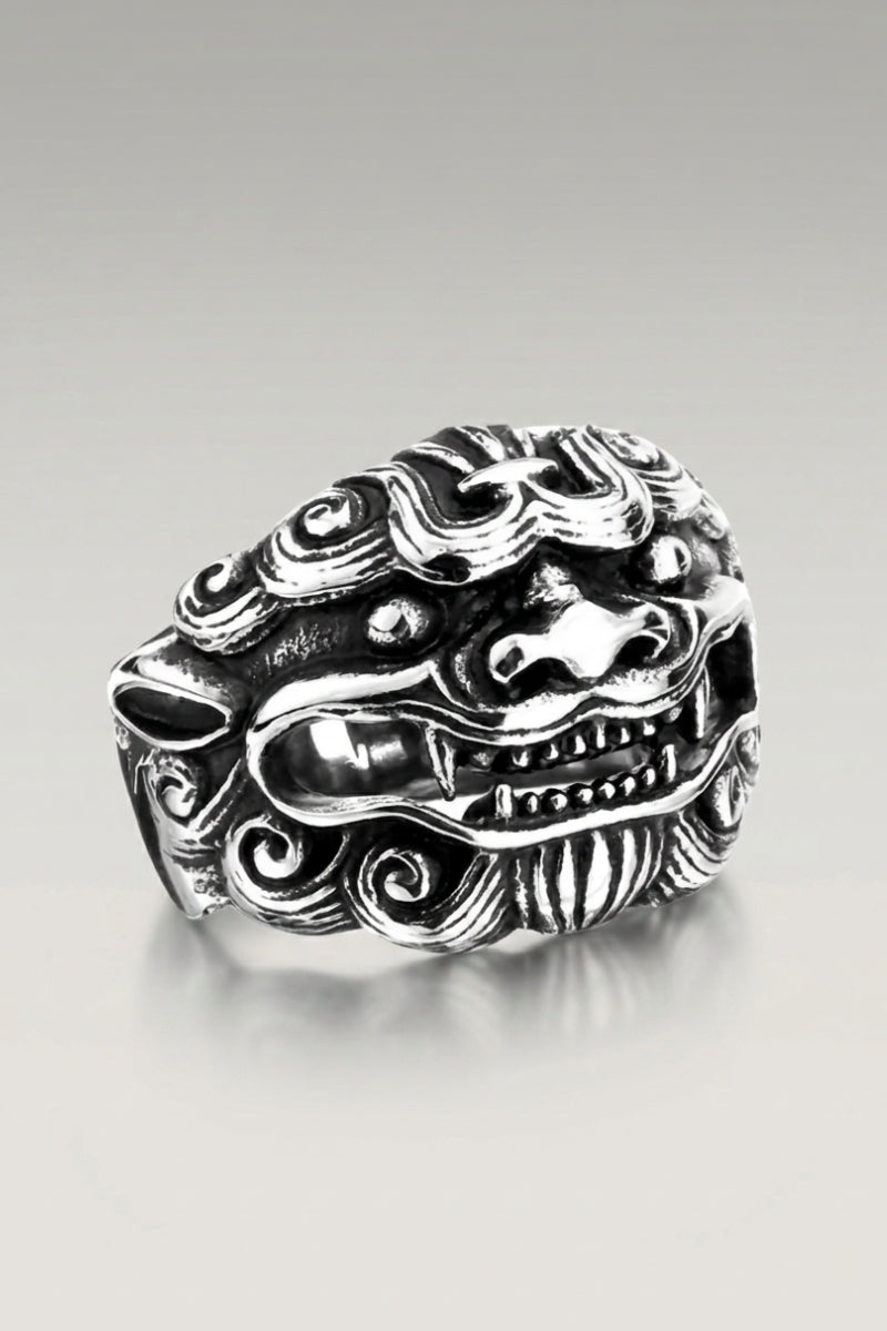 Anillo 'Sypical' — anillo de sello con cabeza de león guardián de melena rizada y colmillos visibles, foto de producto sobre fondo gris claro