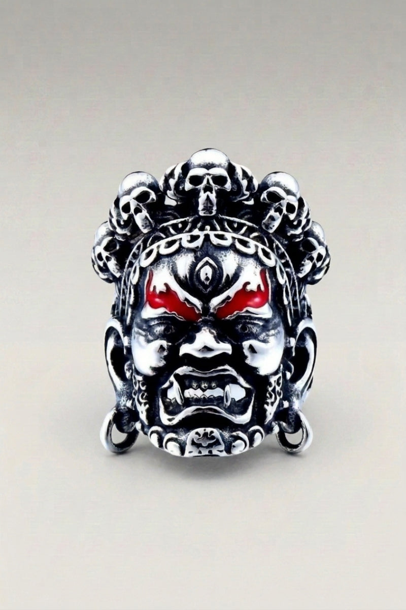Anillo 'Shining' — anillo de sello como máscara pintada en colores vivos, ojos rojos y cejas marcadas, foto de producto sobre fondo gris claro