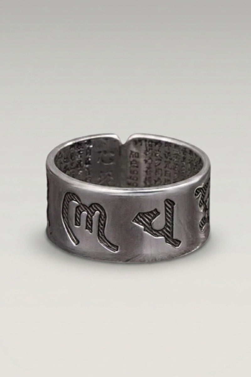 Anillo 'Fujiwa' — anillo ancho de acabado bruto y oscuro con caracteres de mantra en relieve, foto de producto sobre fondo gris claro