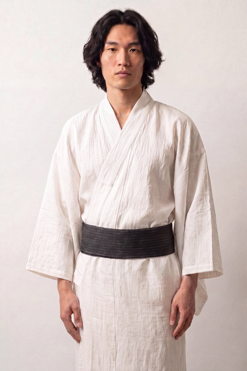 Cinturón obi 'Okayama' ceñido a la cintura sobre un kimono blanco por un modelo masculino — verde azulado muy oscuro con rayas claras regulares