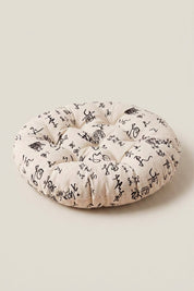 Cojín japonés 'Kiruto' con estampado floral negro sobre fondo crudo — cojín de suelo redondo acolchado en tela estampada, pespuntes regulares y borde mullido