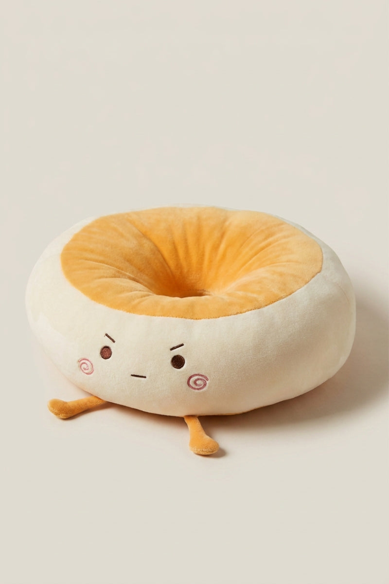Cojín japonés 'Itami' con los ojos redondos — cojín de suelo de peluche crema con forma de personaje de mejillas rosas, centro hundido naranja y piecitos