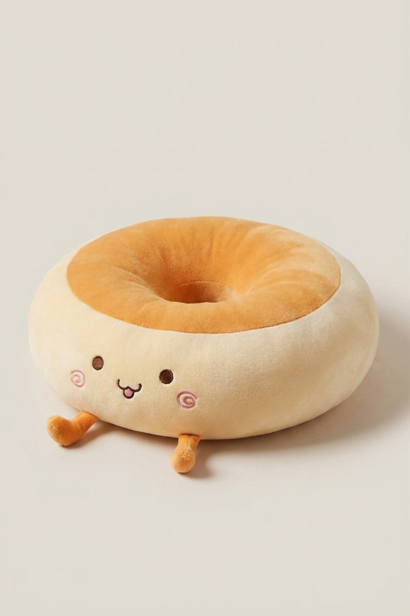 Cojín japonés 'Itami' riendo de frente — cojín de suelo de peluche crema con forma de personaje de mejillas rosas, centro hundido naranja y piecitos