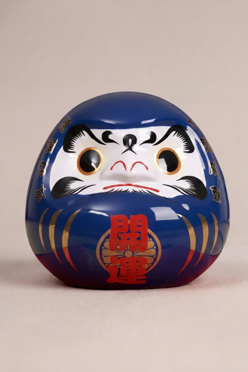 Daruma azul océano de cerámica sobre fondo beige — figura redonda de 11 cm con el kanji 海, ojos en blanco para el rito del deseo