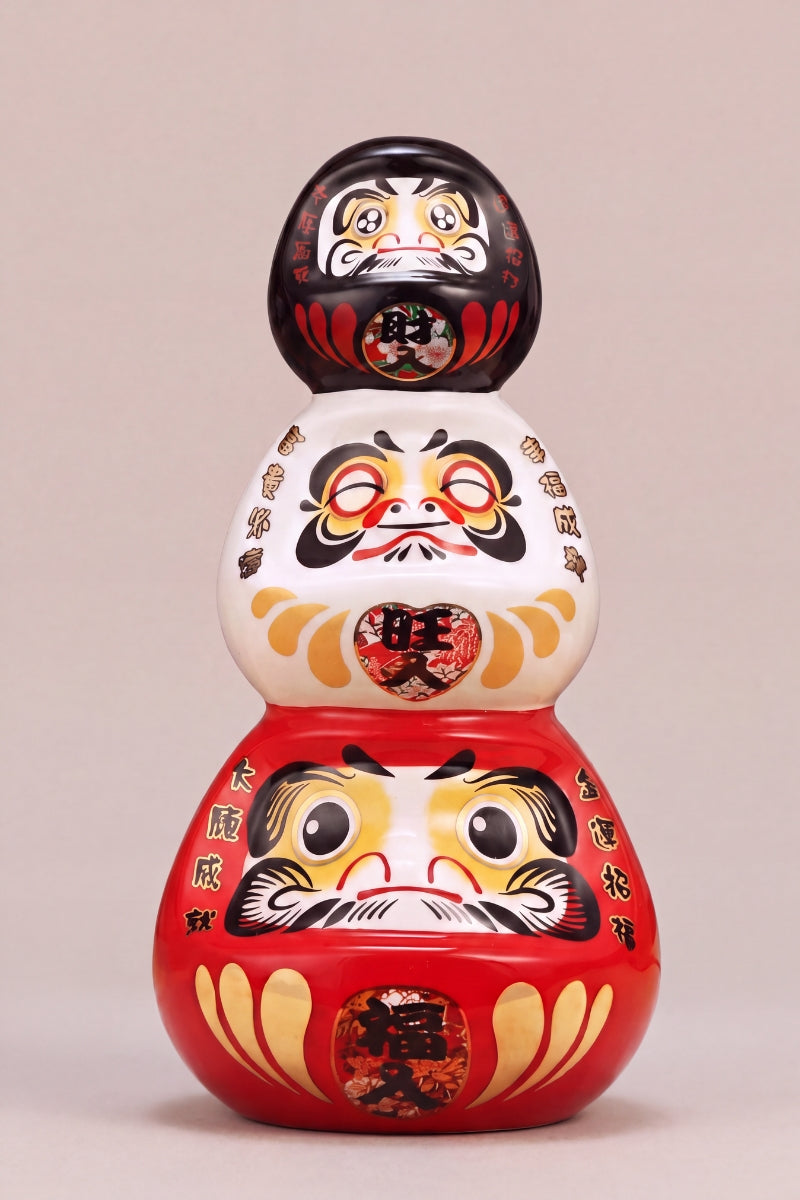 Daruma triple de cerámica sobre fondo beige — figura redonda de 11 cm con el kanji 三福, ojos en blanco para el rito del deseo