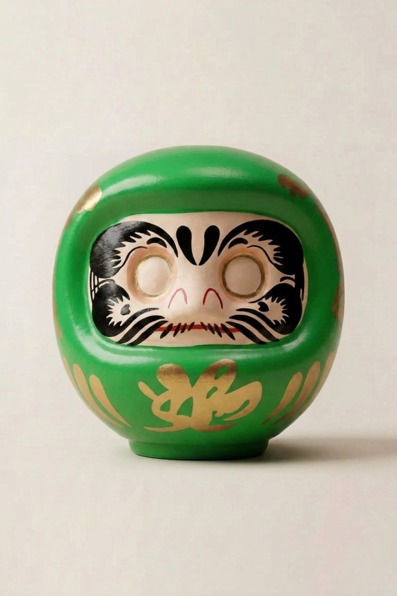 Daruma verde de cerámica sobre fondo beige — figura redonda de 11 cm con el kanji 幸, ojos en blanco para el rito del deseo