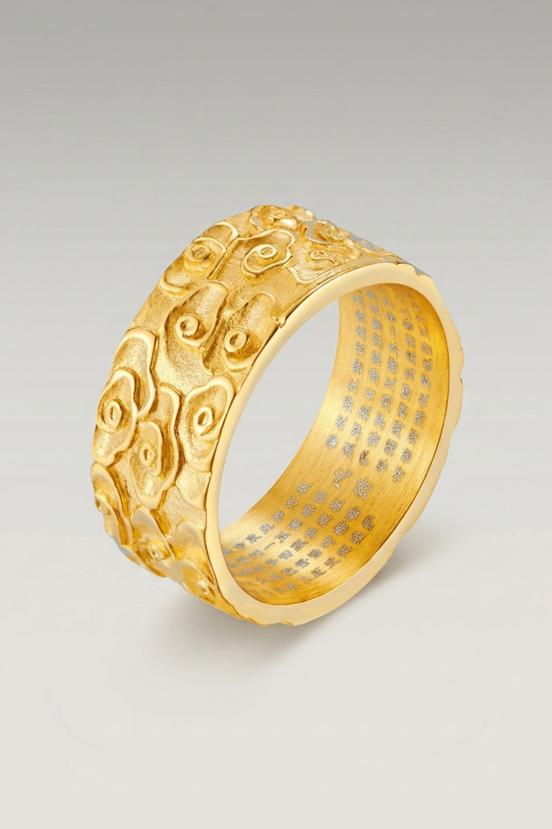 Anillo 'Kumo' en oro — anillo ancho con volutas de nubes talladas en relieve en toda la circunferencia, foto de producto sobre fondo gris claro