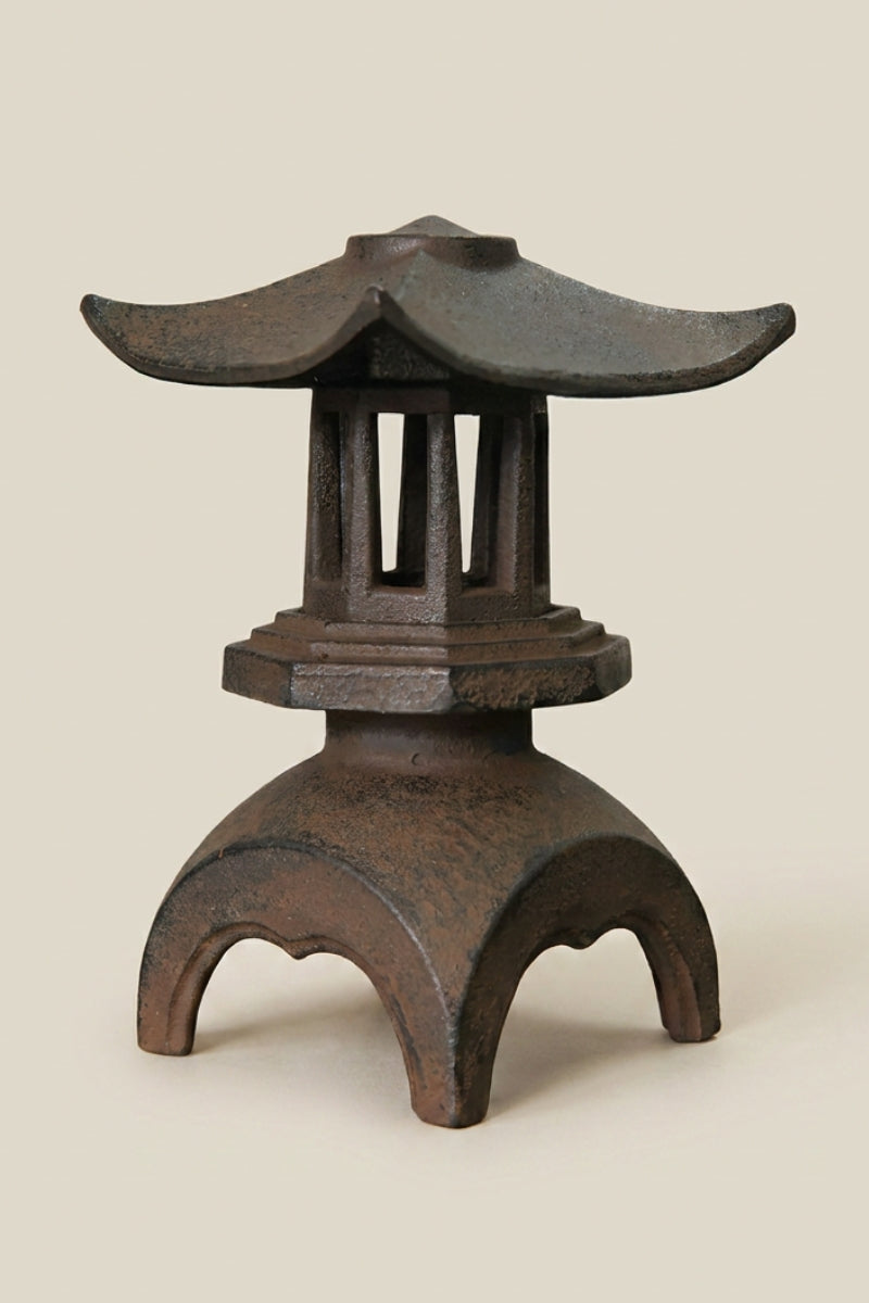 Farol japonés — farol de hierro fundido marrón óxido con tejado ancho curvado y base calada en arcos, foto de producto sobre fondo beige liso