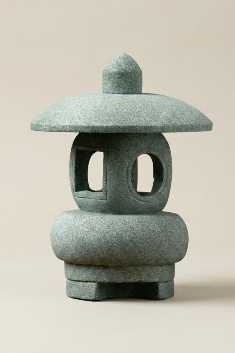 Farol japonés — farol de jardín en piedra verde de formas redondeadas, amplias aberturas ovaladas y base abombada, foto de producto sobre fondo beige liso