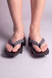 Geta japonés 'Shinshiro' calzada descalza, vista frontal — tira con motivo de olas en blanco y negro sobre plataforma de madera teñida de negro