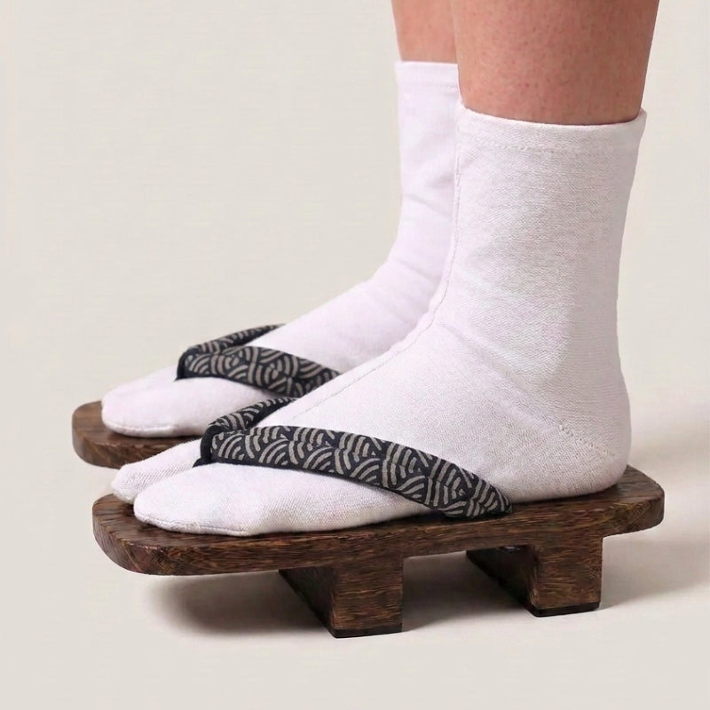 Geta japonés 'Seigaiha' calzada con calcetines tabi blancos, vista de perfil — plataforma de madera oscura, tira con motivo de olas seigaiha en blanco y negro
