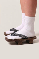Geta japonés 'Seigaiha' calzada con calcetines tabi blancos, vista de perfil — plataforma de madera oscura, tira con motivo de olas seigaiha en blanco y negro
