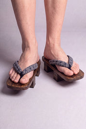 Geta japonés 'Seigaiha' calzada descalza, vista frontal — tira con motivo de olas seigaiha en blanco y negro sobre plataforma de madera oscura