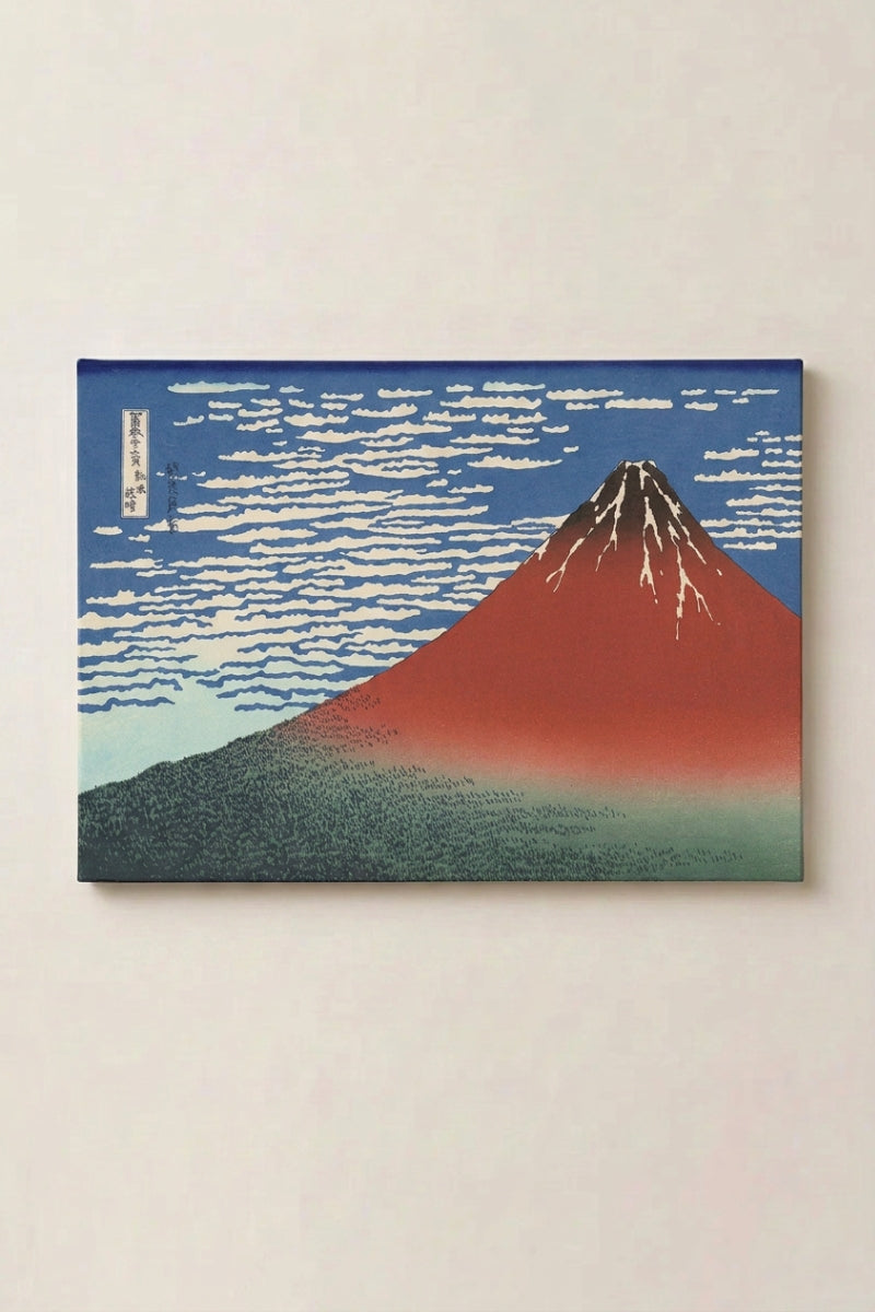 Grabado japonés 'Okoshita' en panel enmarcado sobre pared beige — monte Fuji escarlata sobre un cielo azul con nubes blancas y un bosque oscuro en su base