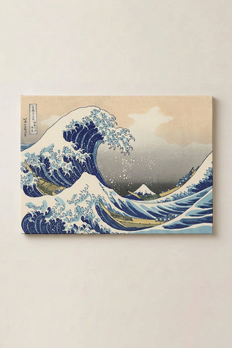 Grabado japonés 'Kanagawa' presentado como panel enmarcado en una pared beige — gran ola de espuma alzándose sobre unas barcas y el diminuto Fuji al fondo