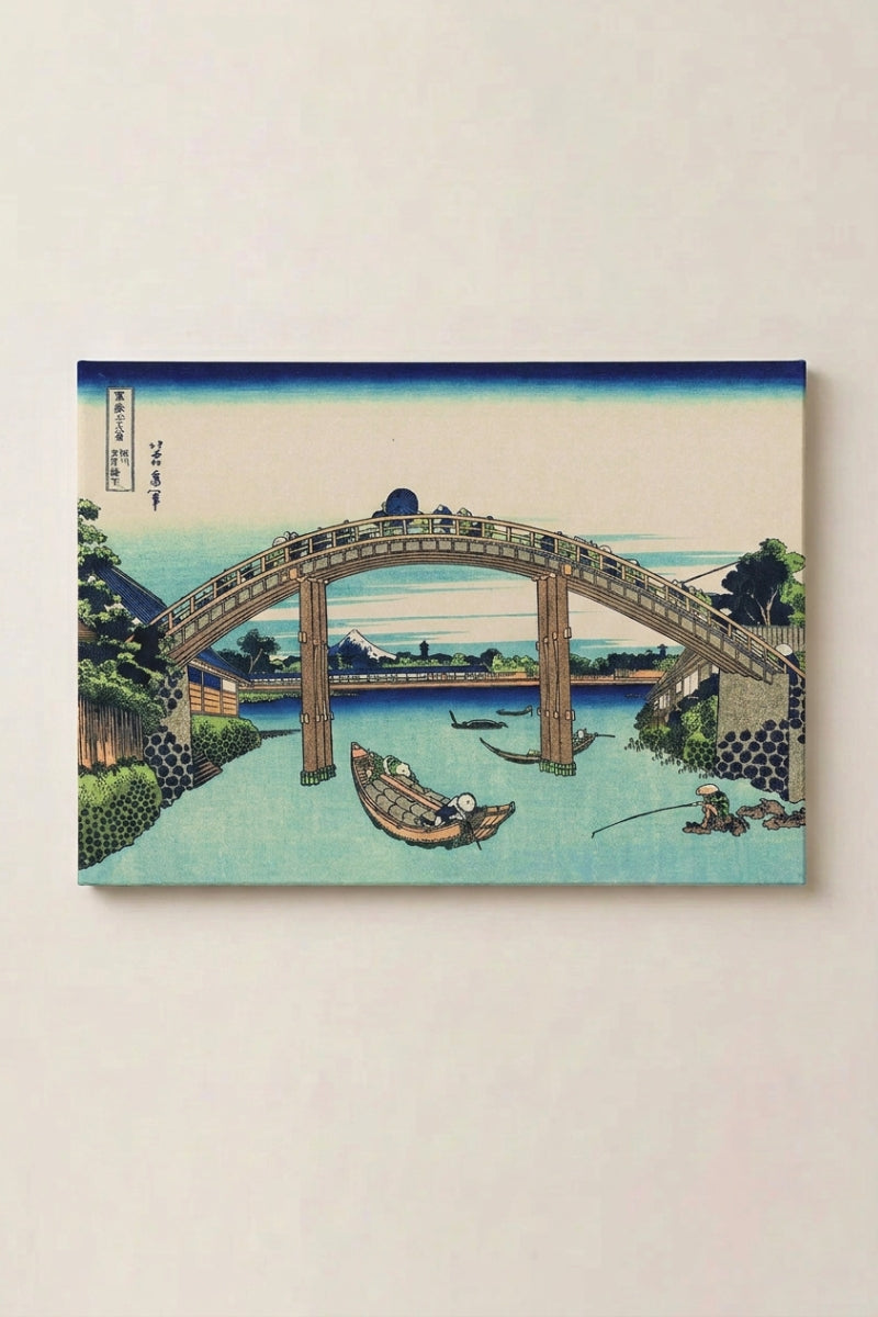 Grabado japonés 'Hashi' en panel enmarcado sobre pared beige — gran puente de madera en arco sobre un río turquesa recorrido por barcas, con el Fuji detrás