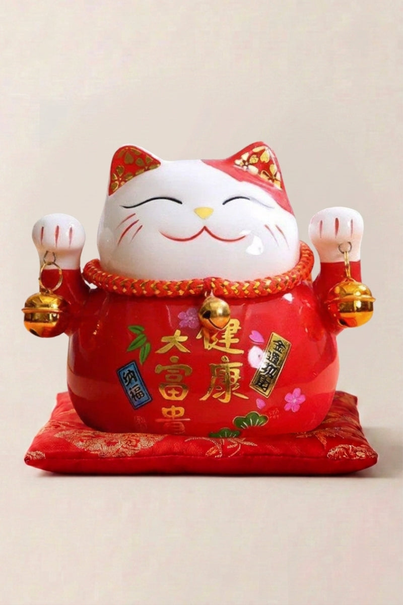 Hucha maneki neko 'Red' de cerámica — gato rojo con motivos florales y placa caligrafiada, ambas patas alzadas, sobre un cojín rojo