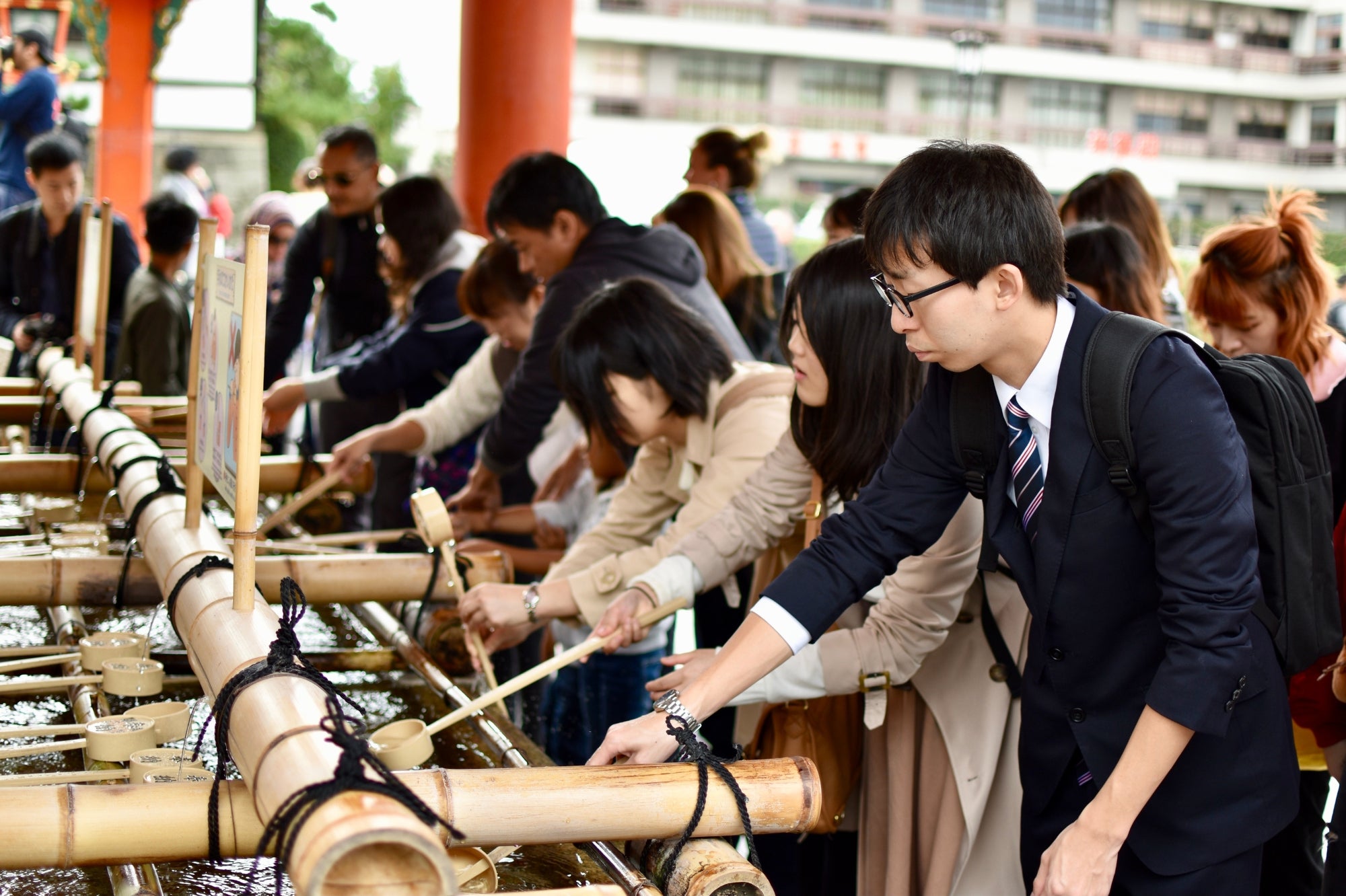 Visitantes japoneses realizan un ritual de purificación con agua en un templo de Kioto, símbolo de las tradiciones espirituales de Japón.