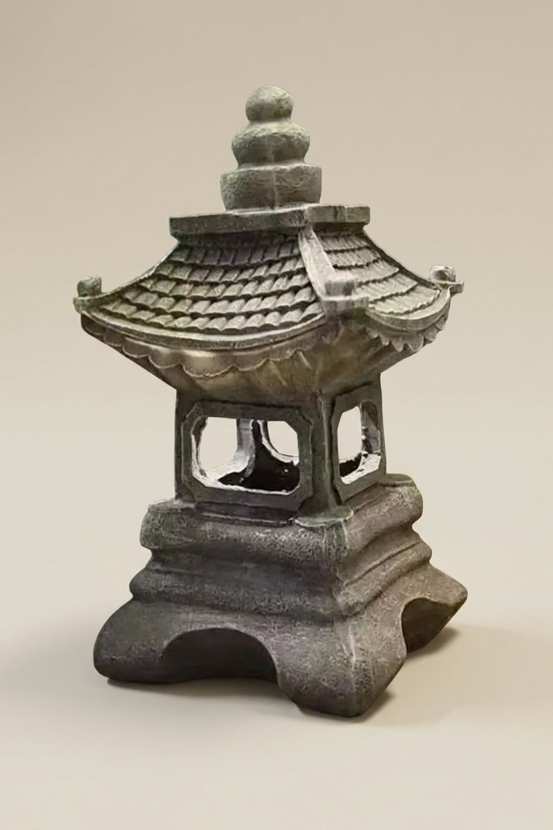 Farol japonés — farol tradicional en bronce con tejados superpuestos, cuerpo calado y base maciza en arcos, foto de producto sobre fondo beige liso