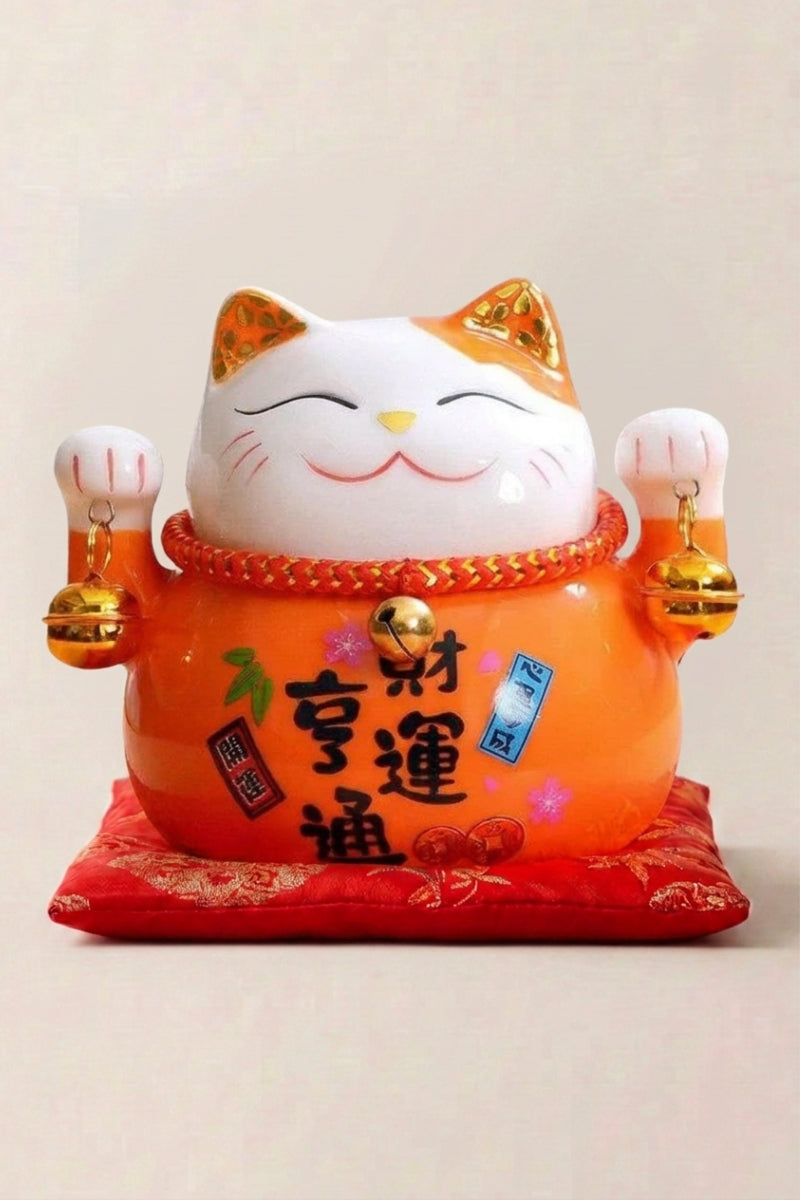 Hucha maneki neko 'Orange Fortune' de cerámica — gato naranja con placa negra caligrafiada y ambas patas alzadas, sobre un cojín rojo