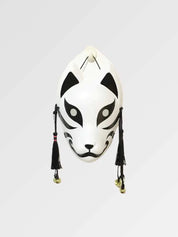 Máscara de gato blanca y negra de frente sobre fondo gris — felino blanco con amplias zonas negras alrededor de los ojos, borlas negras y cascabeles