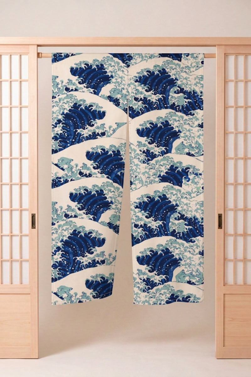 Noren japonés 'Kanagawa Wave' colgado en el marco de una puerta de madera clara — grandes olas de Hokusai repetidas en azul y blanco sobre fondo crema