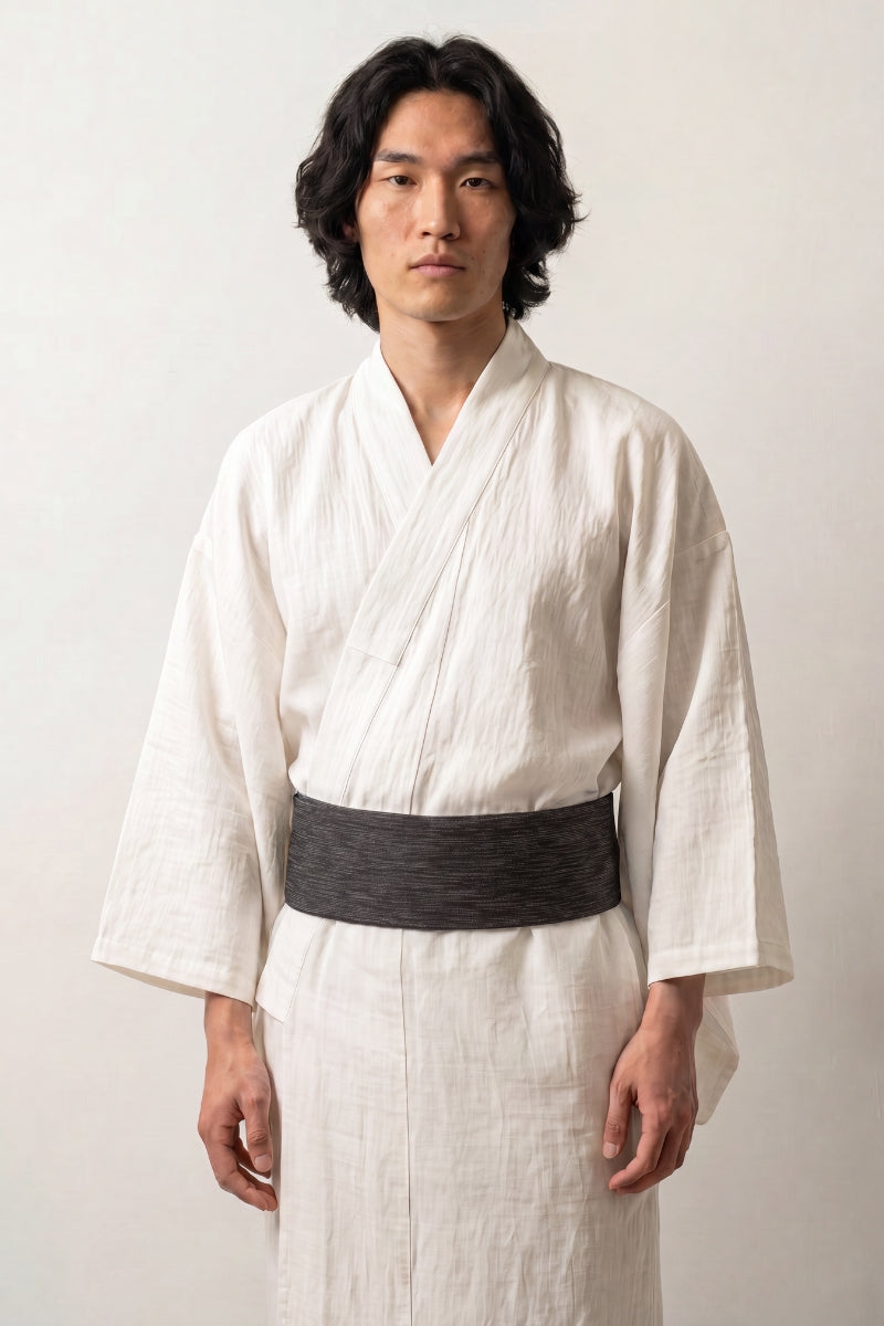 Cinturón obi 'Nagoya' ceñido a la cintura sobre un kimono blanco por un modelo masculino — negro veteado con líneas horizontales irregulares más claras