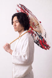 Sombrilla japonesa 'Kanji' abierta y sostenida por un modelo con kimono blanco — tela blanca con ciruelo rojo y negro acompañado de caligrafía