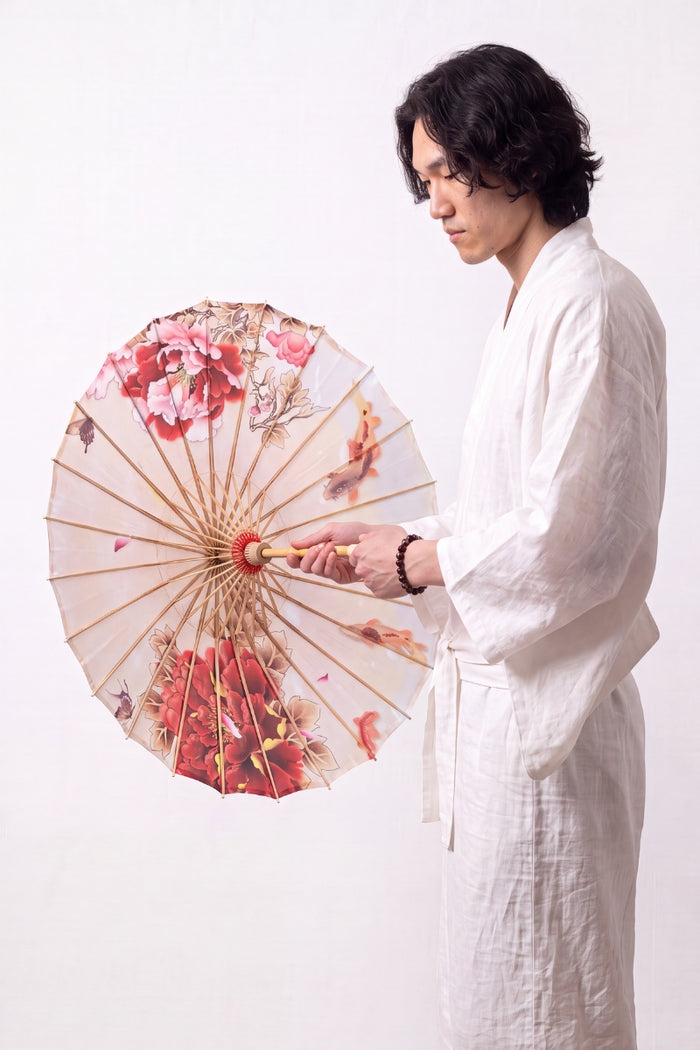 Sombrilla japonesa 'Blossom' abierta y sostenida por un modelo con kimono blanco — tela blanca con ramas de cerezo rosas que corren hacia el centro