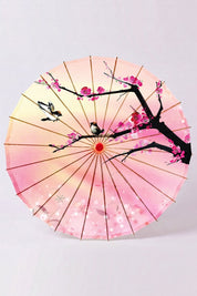 Sombrilla japonesa 'Sakura Fleuri' vista desde abajo — tela rosa en degradado con rama oscura y flores de cerezo, armazón a la vista