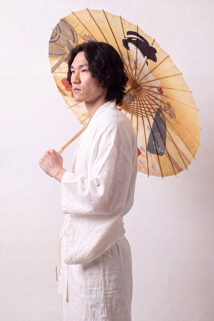 Sombrilla japonesa 'Take-Amino' abierta y sostenida por un modelo con kimono blanco — tela amarillo ocre con retrato de mujer en kimono al gusto de la estampa