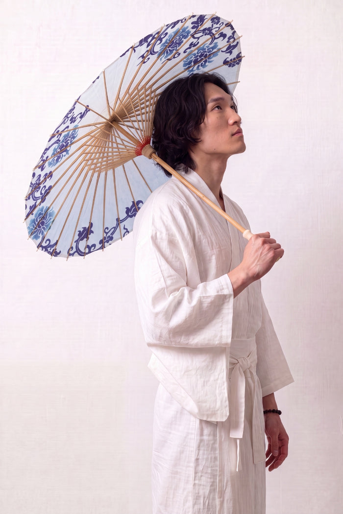 Sombrilla japonesa 'Shiroi' abierta y sostenida por un modelo con kimono blanco — tela blanca con motivo floral azul dispuesto en corona