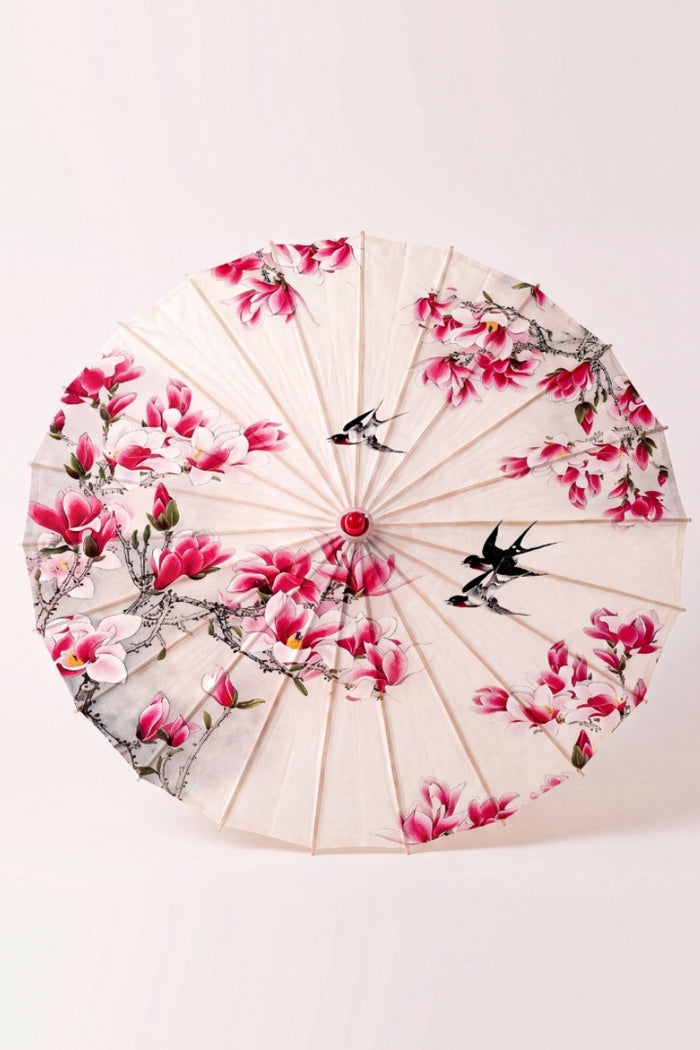 Sombrilla japonesa 'Nomikomu' vista desde arriba, abierta en plano — tela crema cubierta de flores de cerezo rosas, varillas que irradian desde el buje
