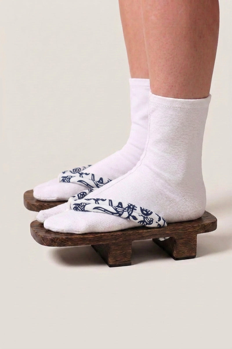 Geta japonés 'Okayama' calzada con calcetines tabi blancos, vista de perfil — plataforma de madera marrón, tira blanca con motivo floral azul noche