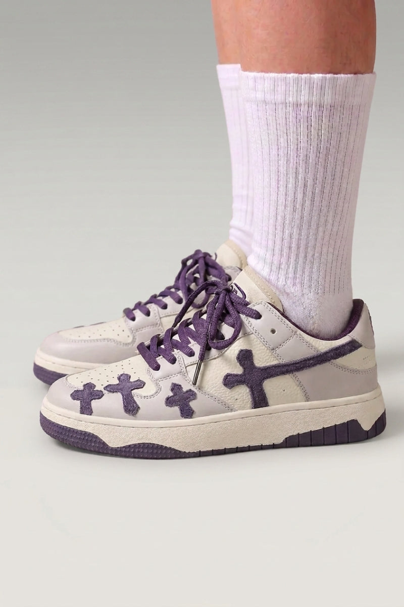 Zapatillas bajas 'Shiro' en violeta — cruces en relieve en los laterales y cordones gruesos a juego, con calcetines blancos sobre fondo de estudio gris