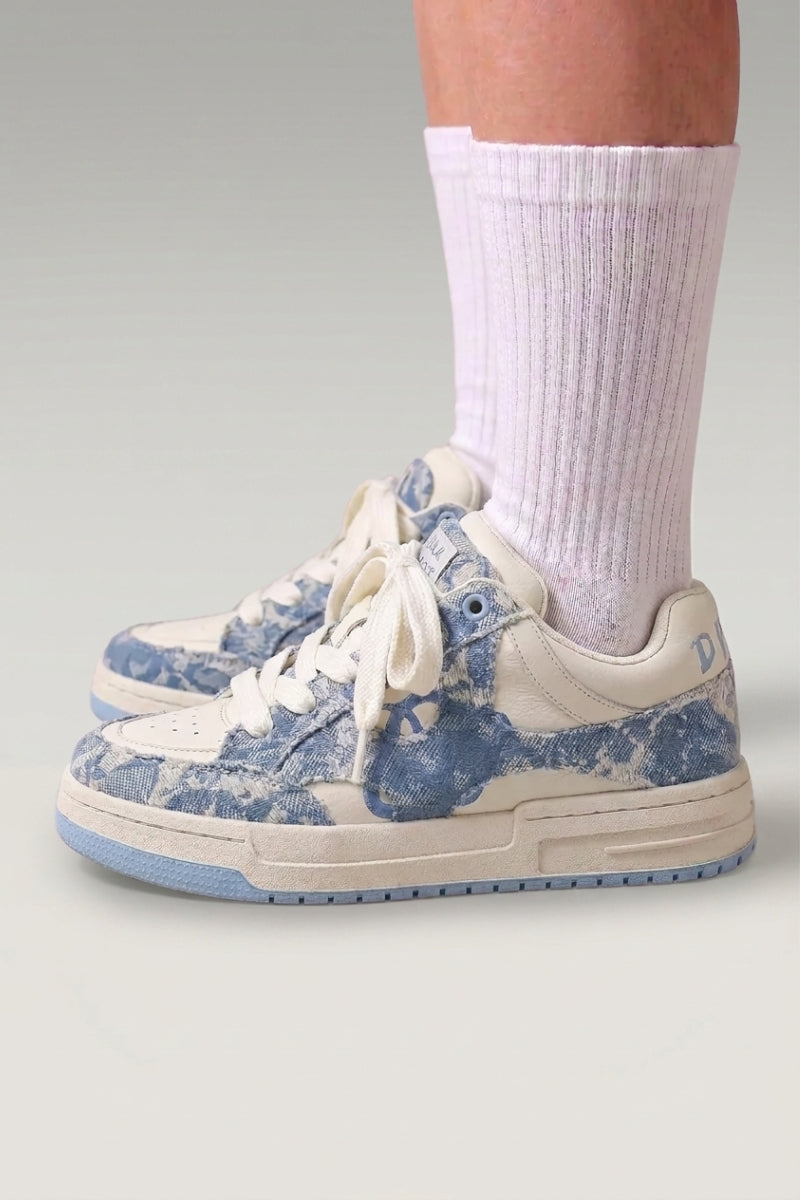 Zapatillas bajas 'Yuki' en azul — lona lisa sin pespuntes visibles y suela plana en contraste, con calcetines blancos sobre fondo de estudio gris