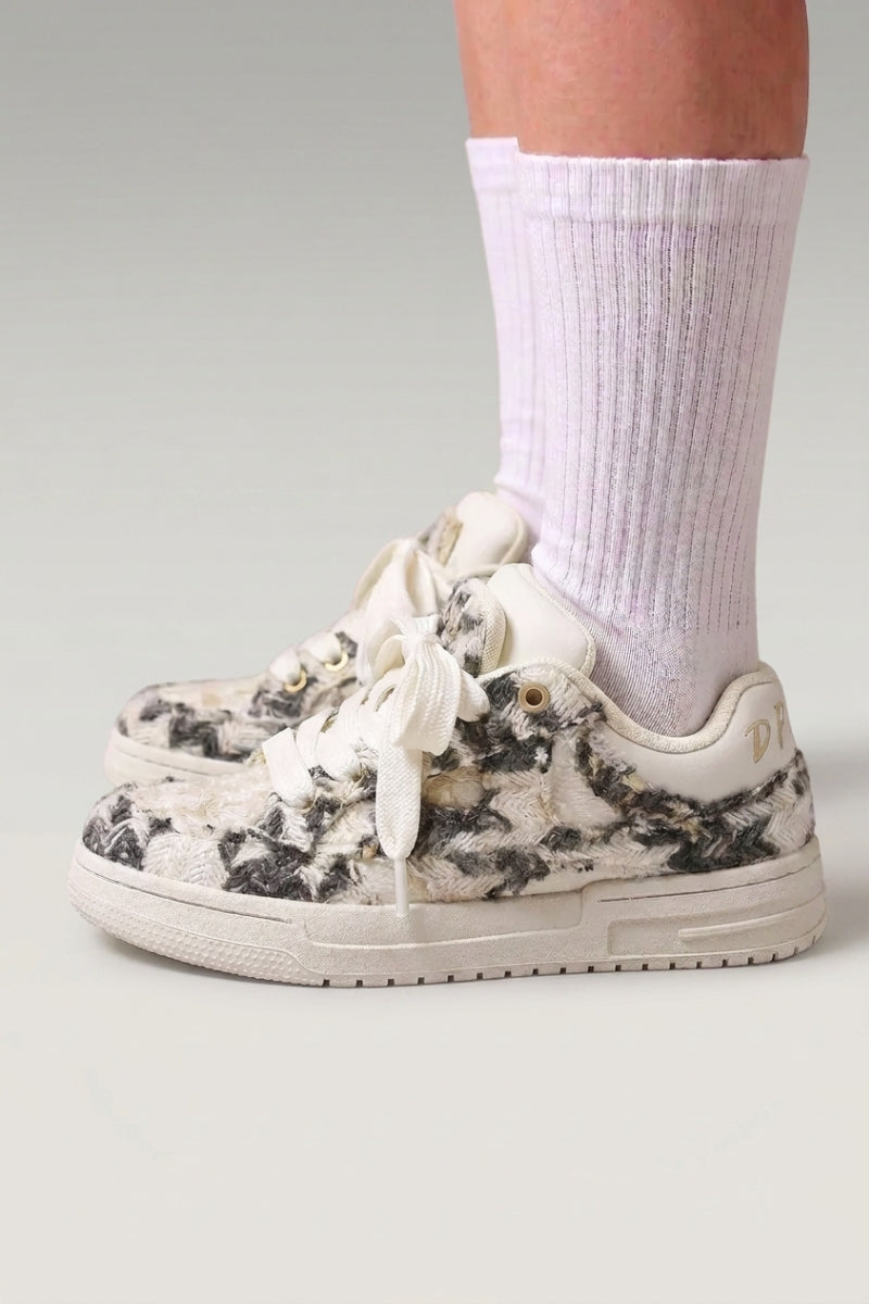 Zapatillas bajas 'Yuki' en gris — lona lisa sin pespuntes visibles y suela plana en contraste, con calcetines blancos sobre fondo de estudio gris