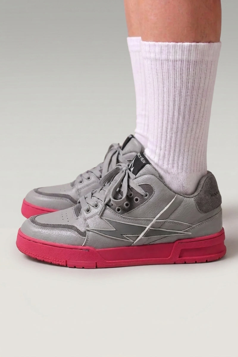 Zapatillas chunky 'Inazuma' en rosa — corte blanco y gris sobre una suela monocroma viva, con calcetines blancos sobre fondo de estudio gris