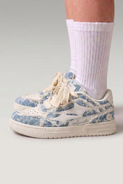 Zapatillas bajas 'Seiryu' en azul — lona lavada con estampado floral difuminado y suela cupsole crema, con calcetines blancos sobre fondo de estudio gris