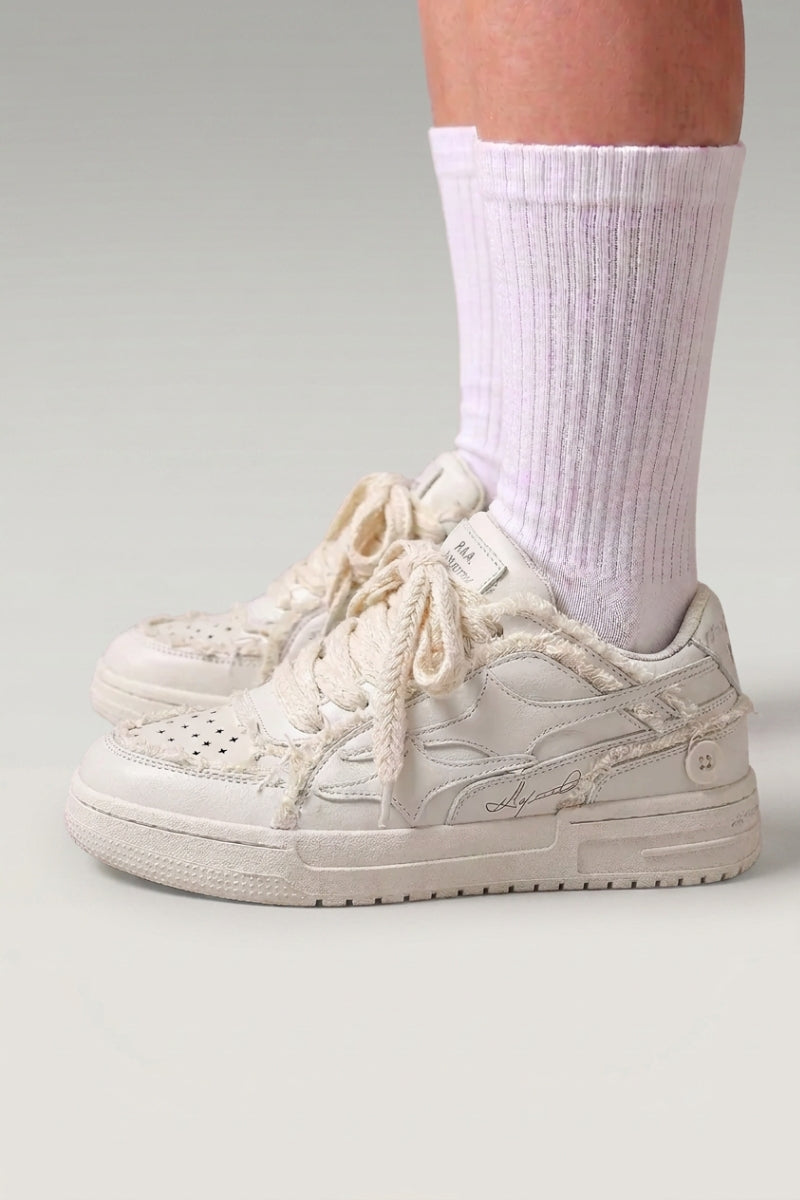 Zapatillas bajas 'Seiryu' en blanco — lona lavada con estampado floral difuminado y suela cupsole crema, con calcetines blancos sobre fondo de estudio gris